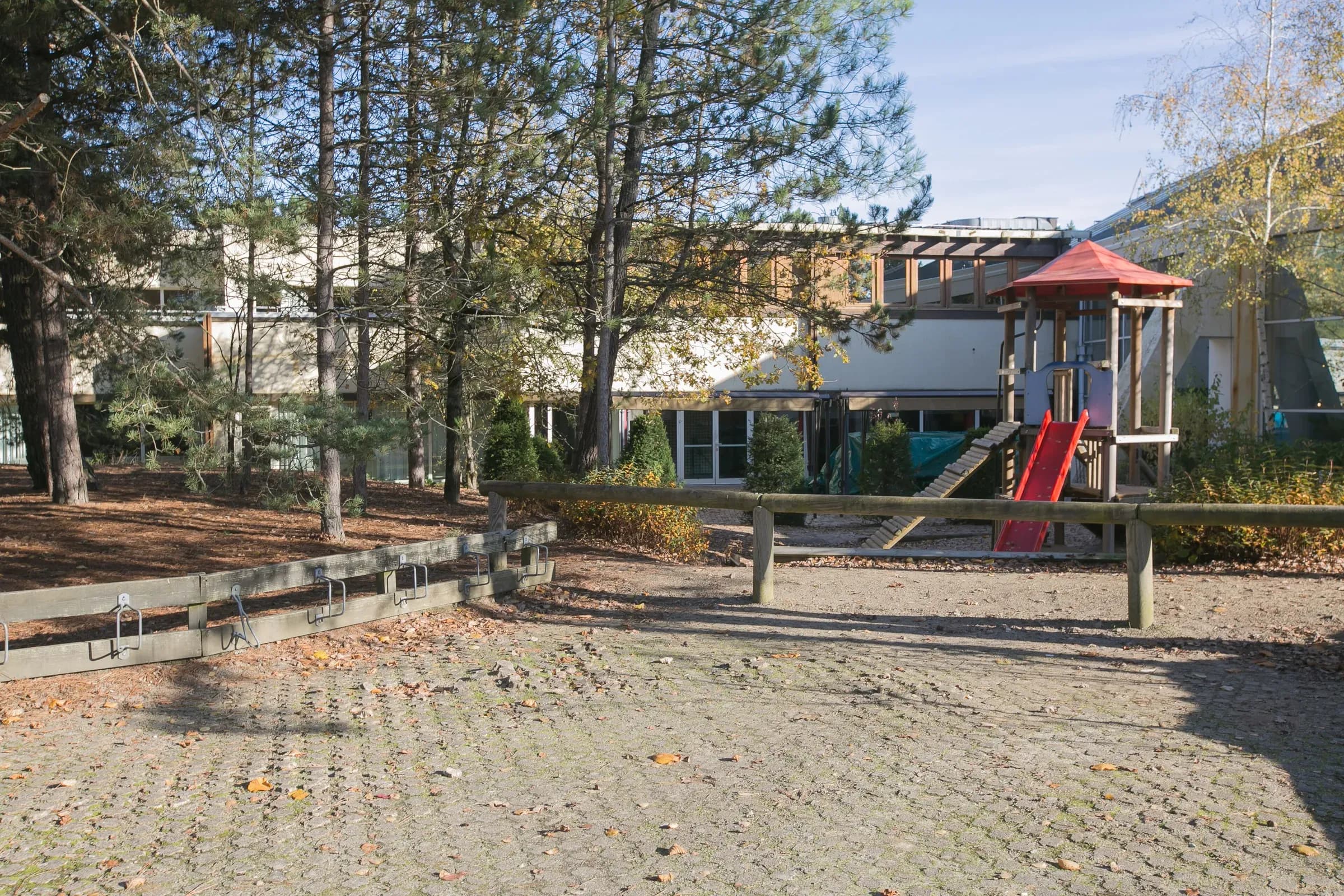 Playground and building of the Hauts de Bruyères estate among the pine trees