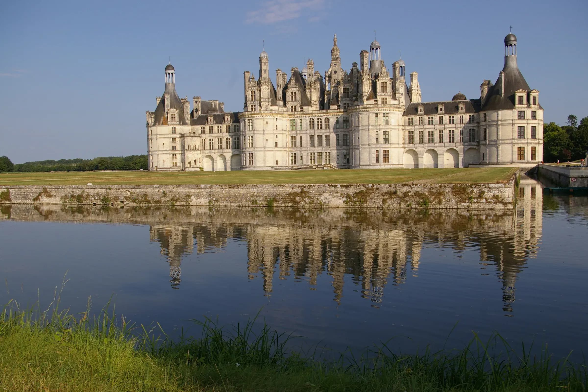 Château de Chambord in golden sunlight, mirrored in the still water of the Cosson