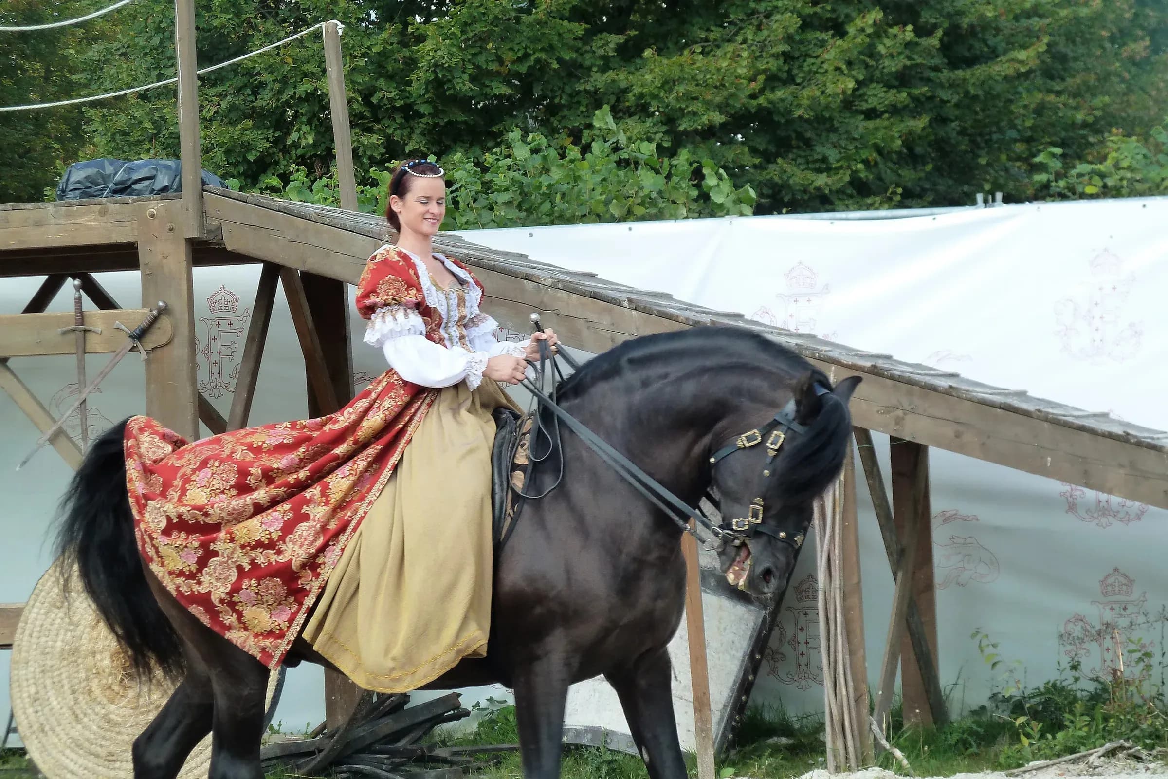 Cavalière en robe rouge brodée sur un cheval noir pendant le spectacle équestre de Chambord