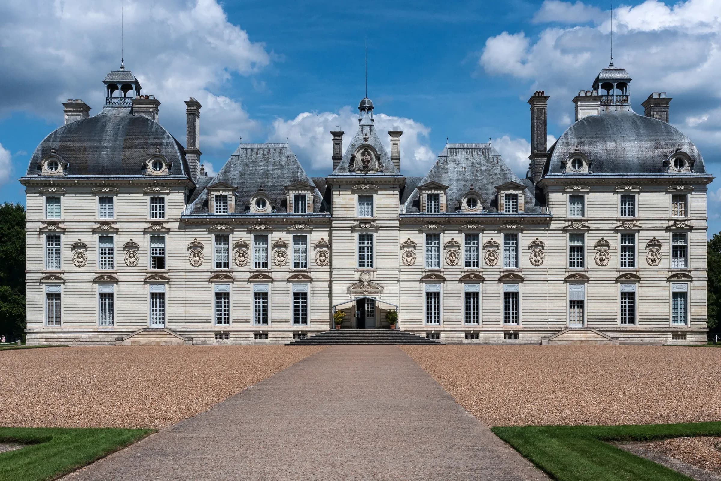 Façade classique blanche du château de Cheverny face à l'allée de gravier sous un ciel bleu