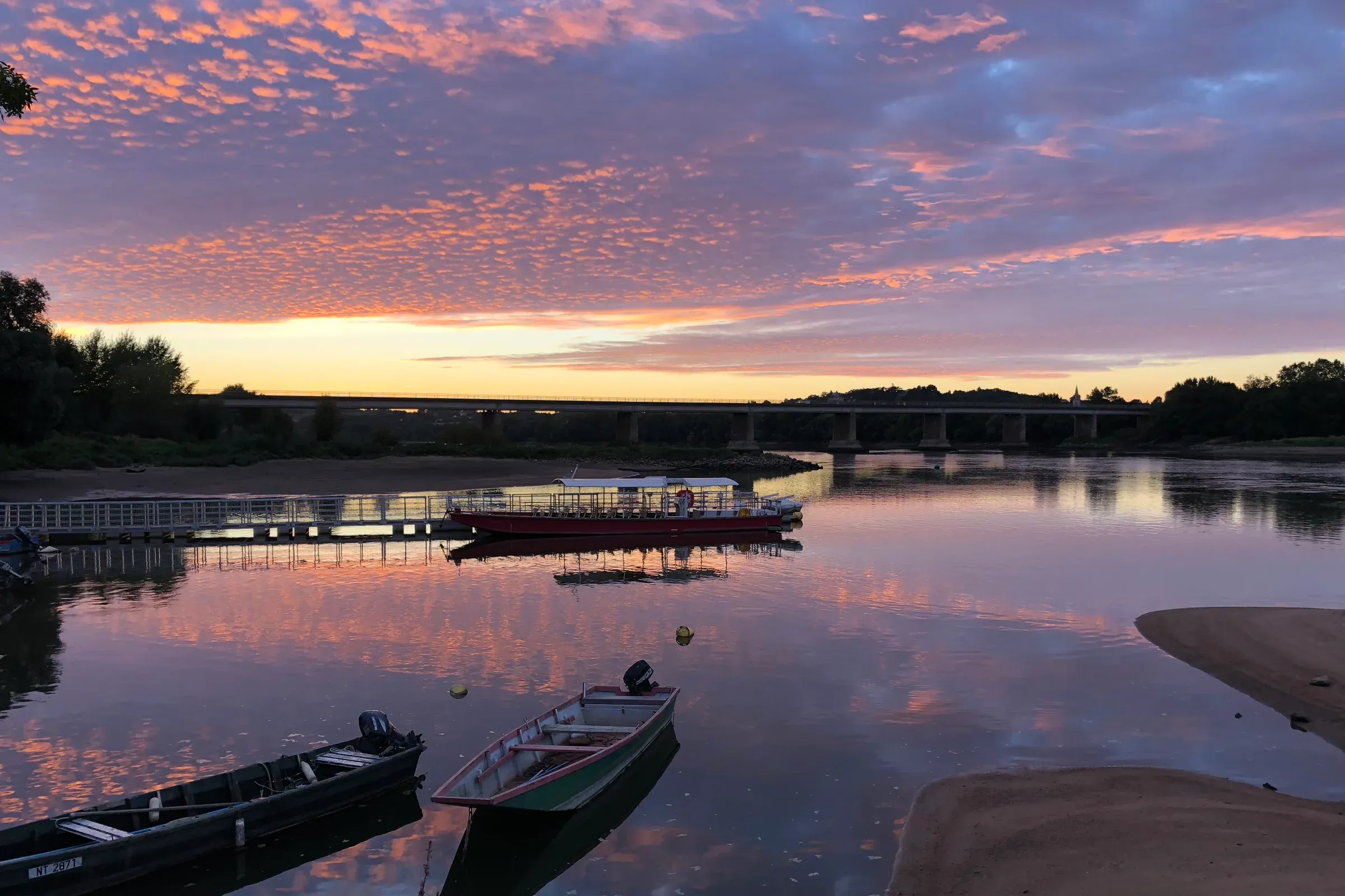 Boats moored on the Loire under a pink sky at sunset