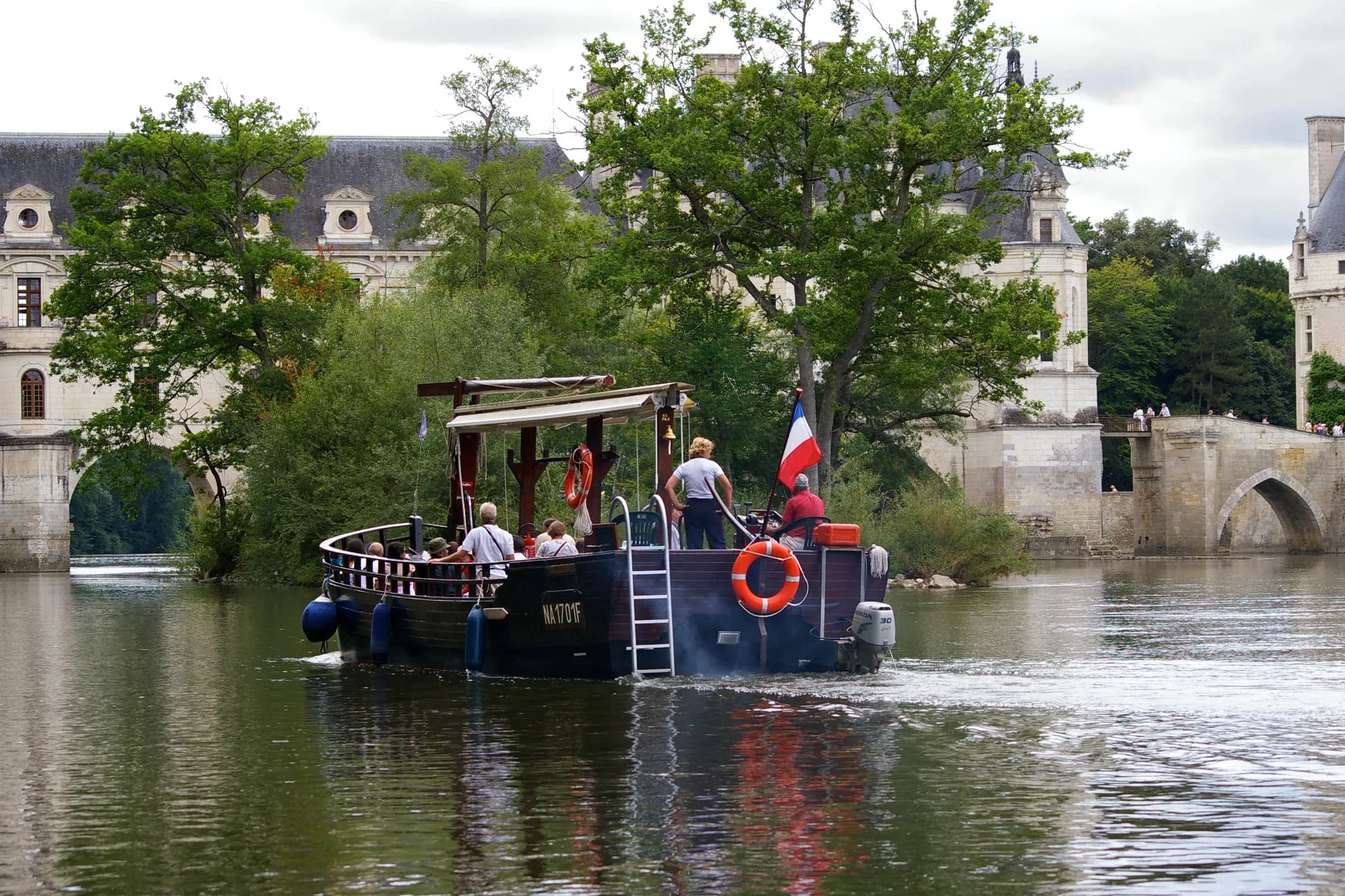 Cruise boat and its passengers on the Cher in front of the Château de Chenonceau
