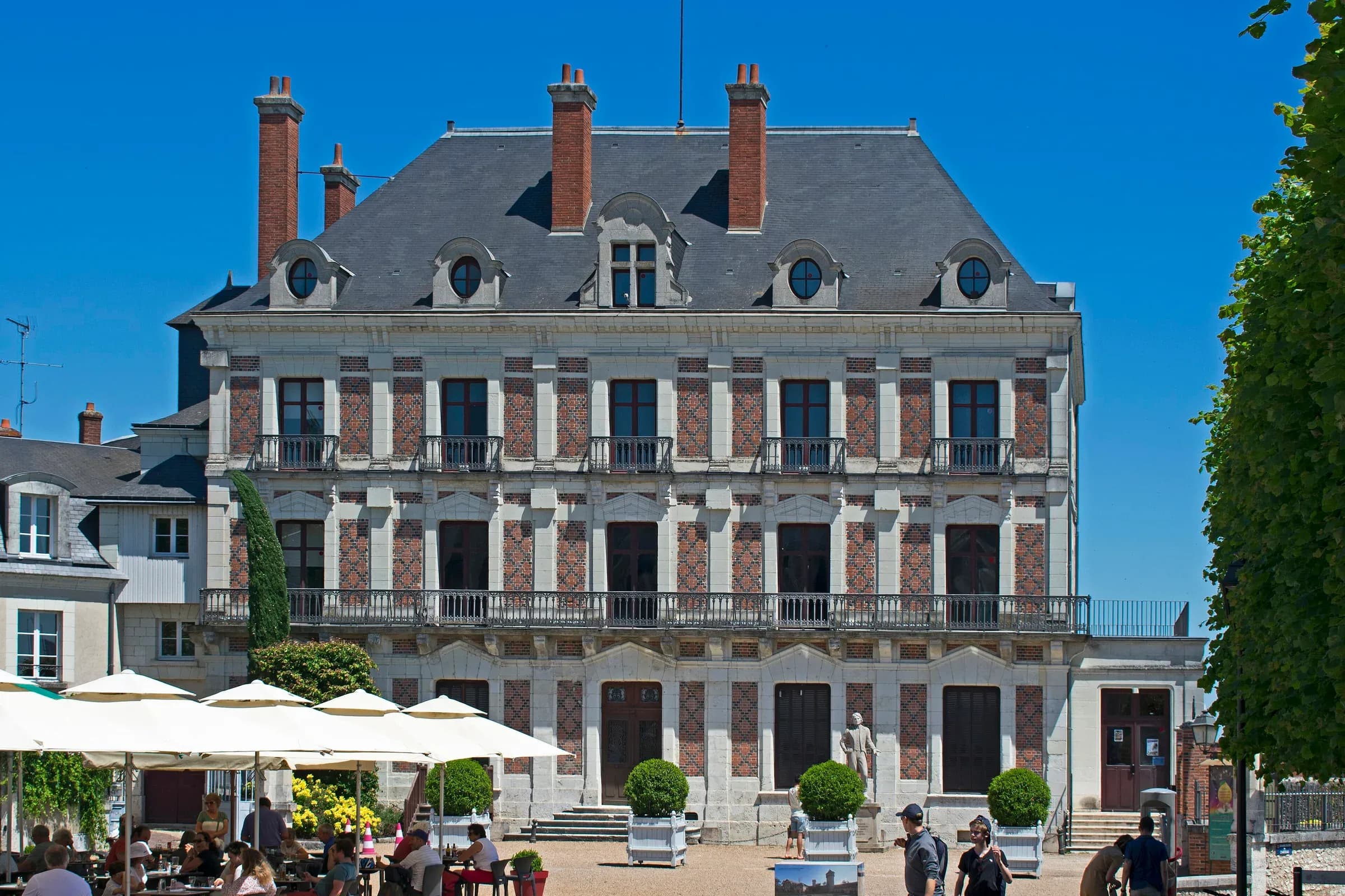 Façade de brique et pierre de la Maison de la Magie à Blois, sous un ciel bleu