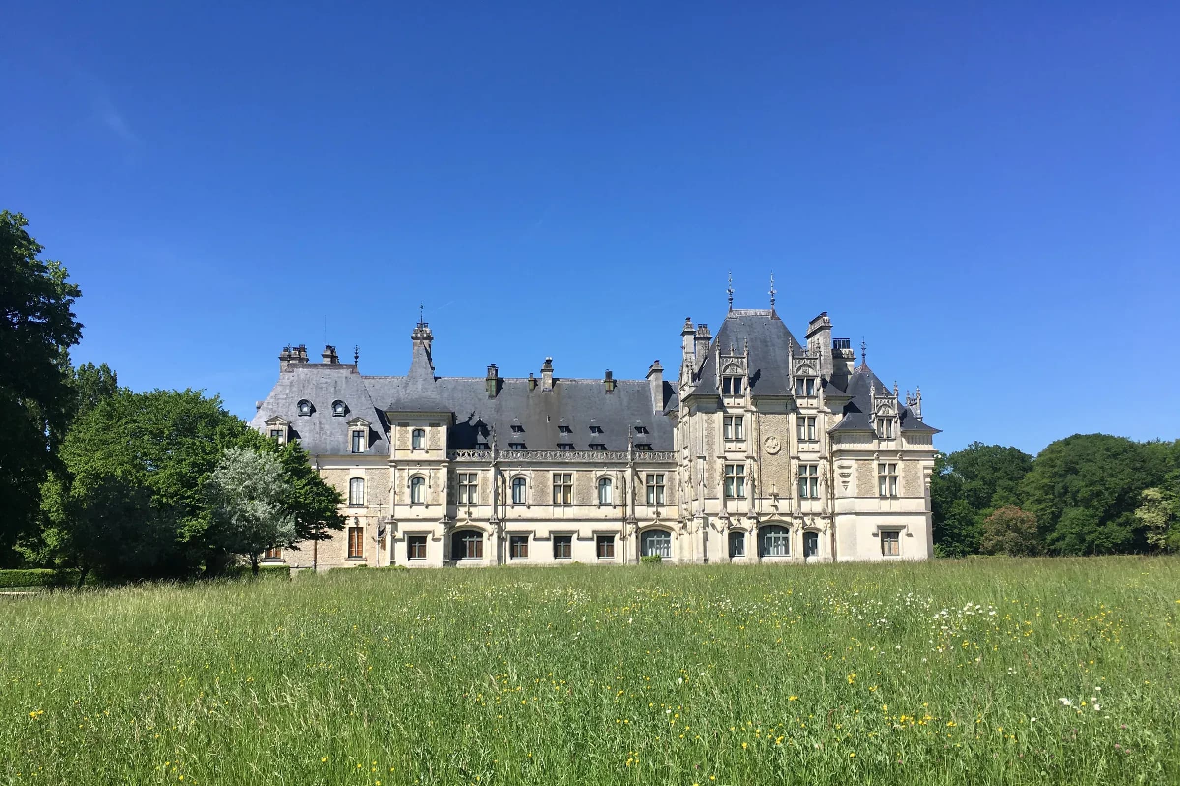 Château de Menetou-Salon au bout d'une prairie, sous un ciel bleu
