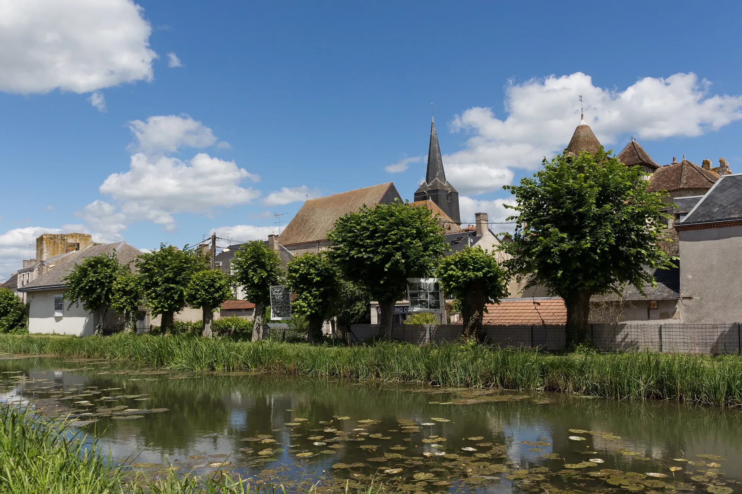 Clocher et maisons de Mennetou-sur-Cher derrière le canal bordé de nénuphars