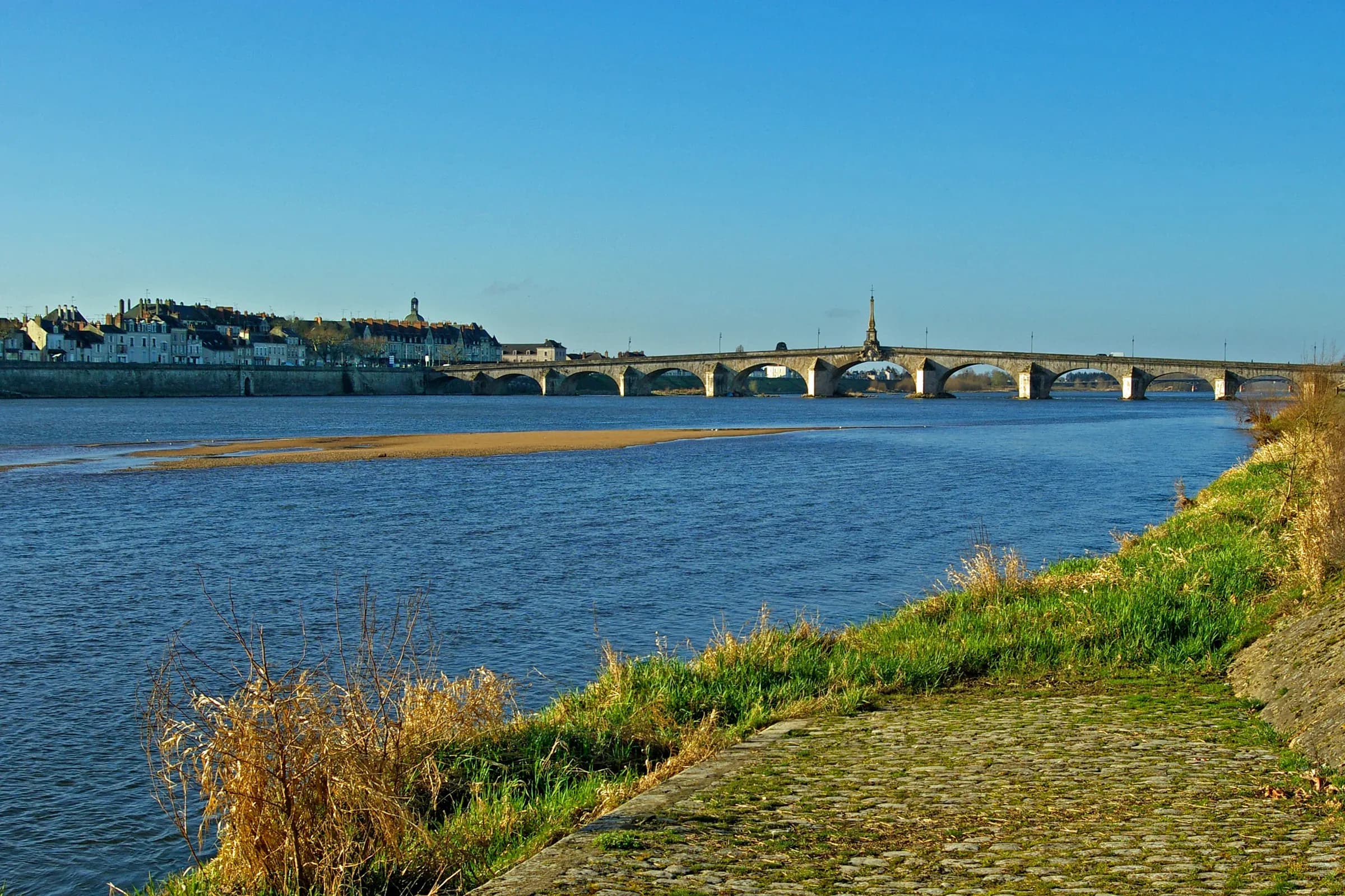 La Loire et le pont Jacques-Gabriel à Blois, vus depuis la rive sous un ciel bleu