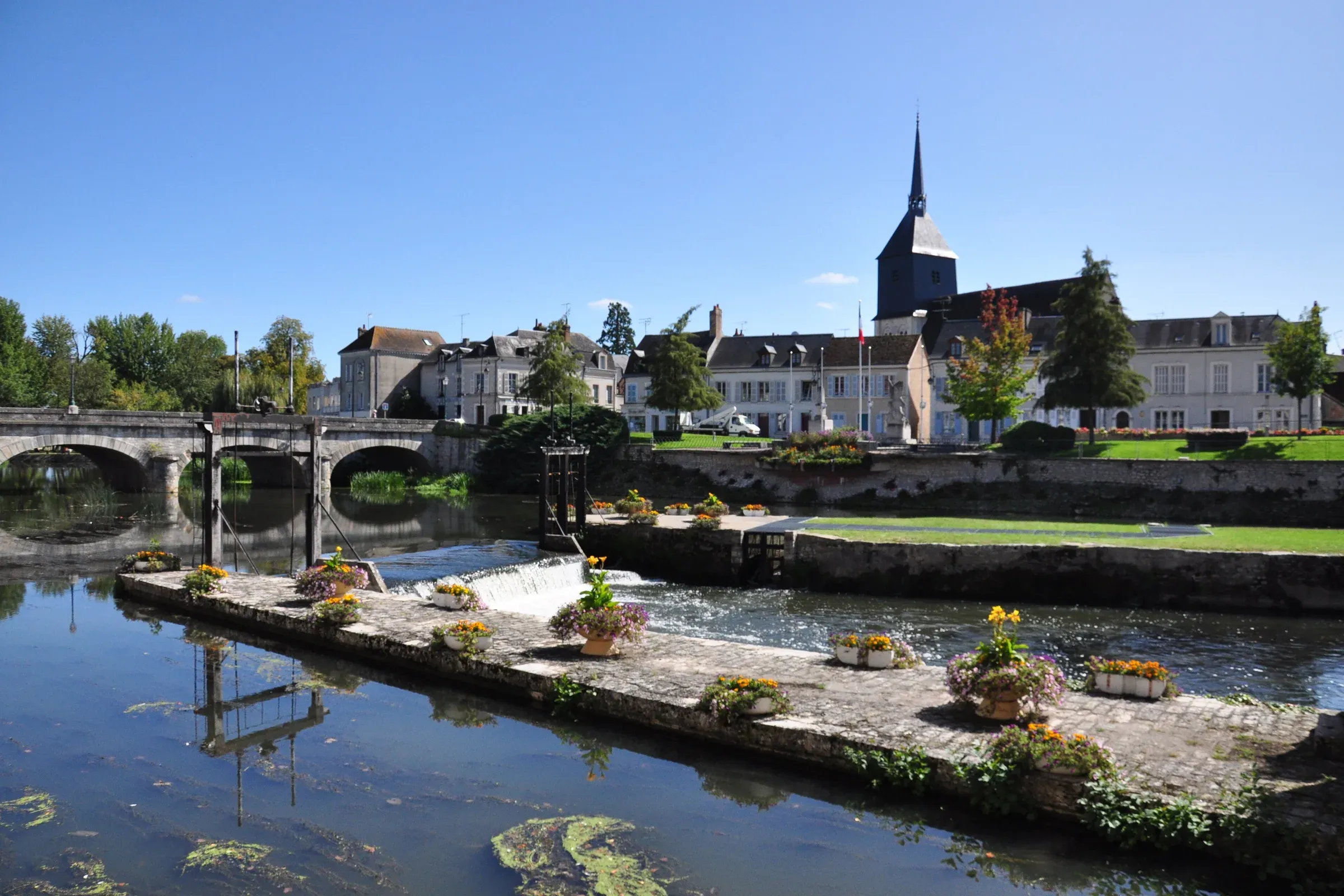 La Sauldre à Romorantin-Lanthenay, son déversoir fleuri, le pont et le clocher de l'église Saint-Étienne