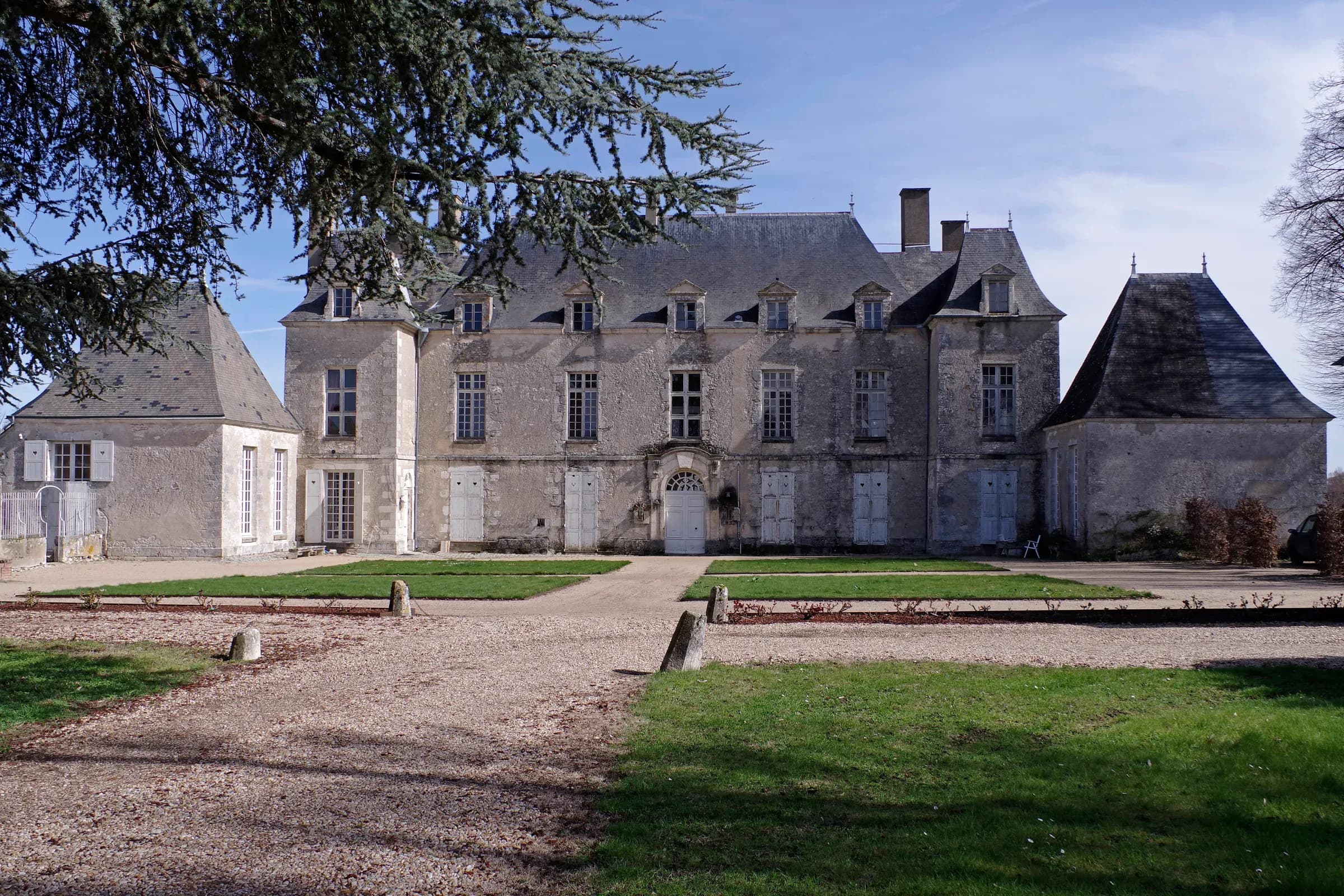 Château de Quincy, dans le Cher, au bout de son allée de gravier sous un ciel bleu