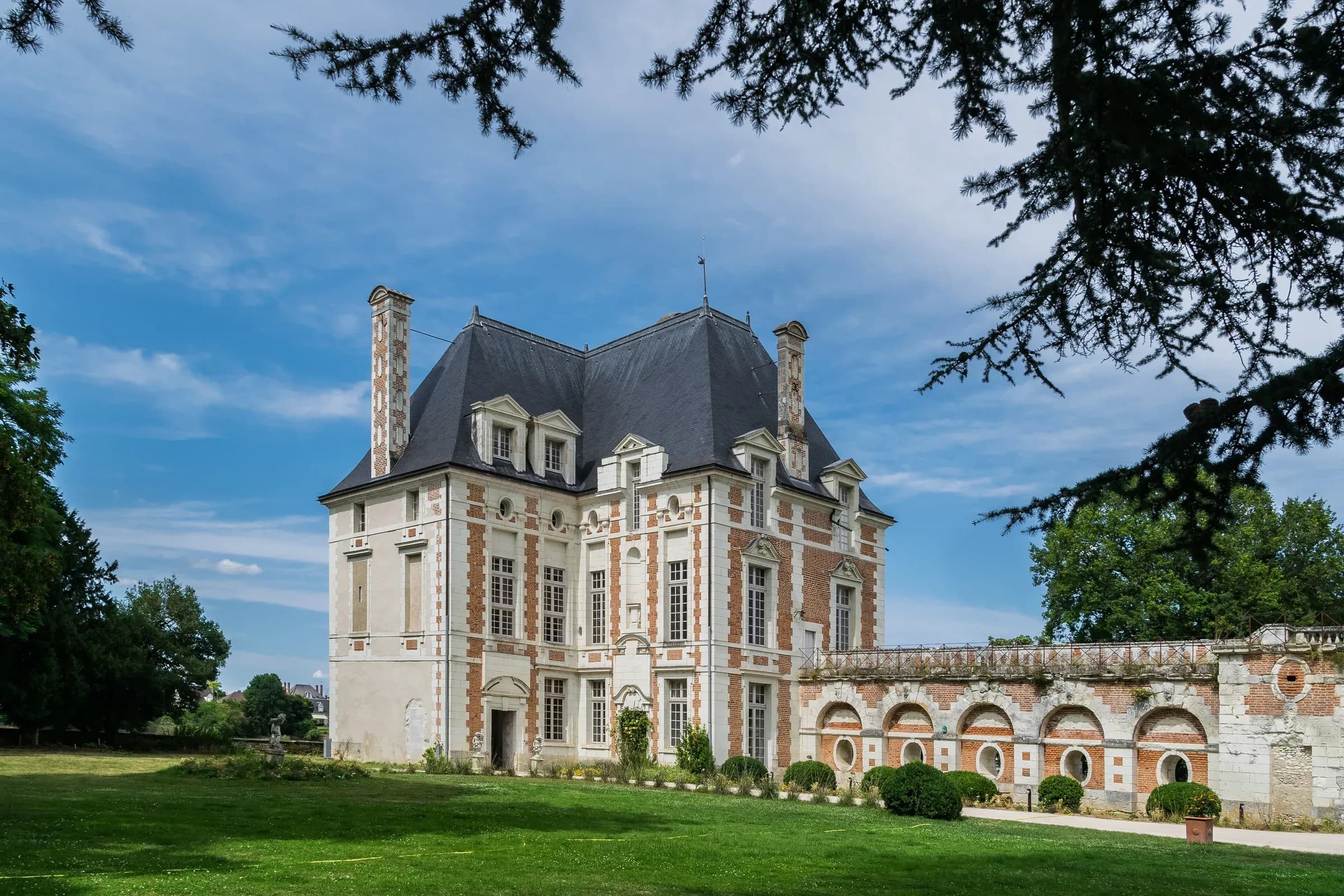 Pavillon Renaissance de brique et pierre du château de Selles-sur-Cher, encadré par les branches d'un cèdre