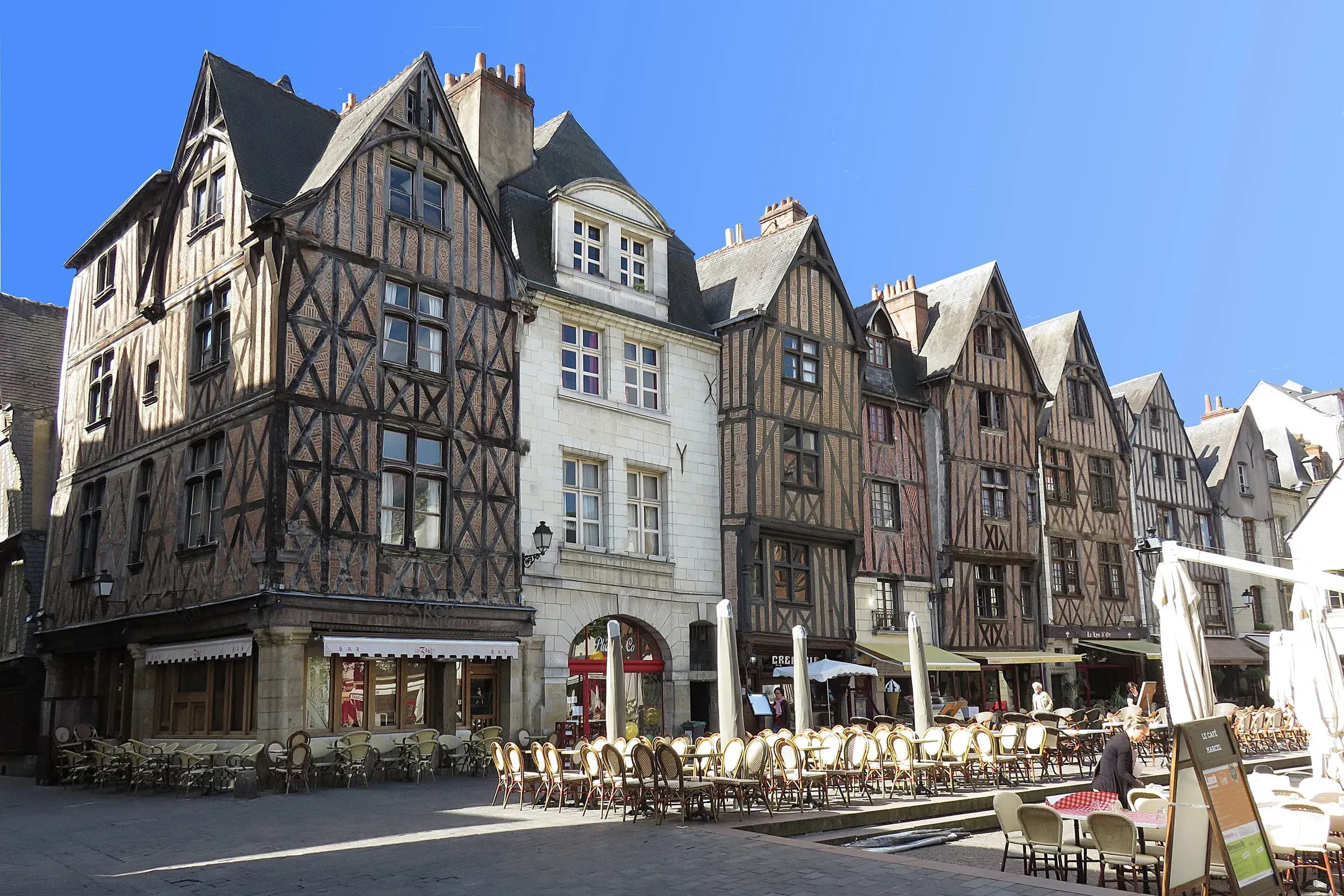 Half-timbered houses and café terraces on Place Plumereau in Tours under a blue sky