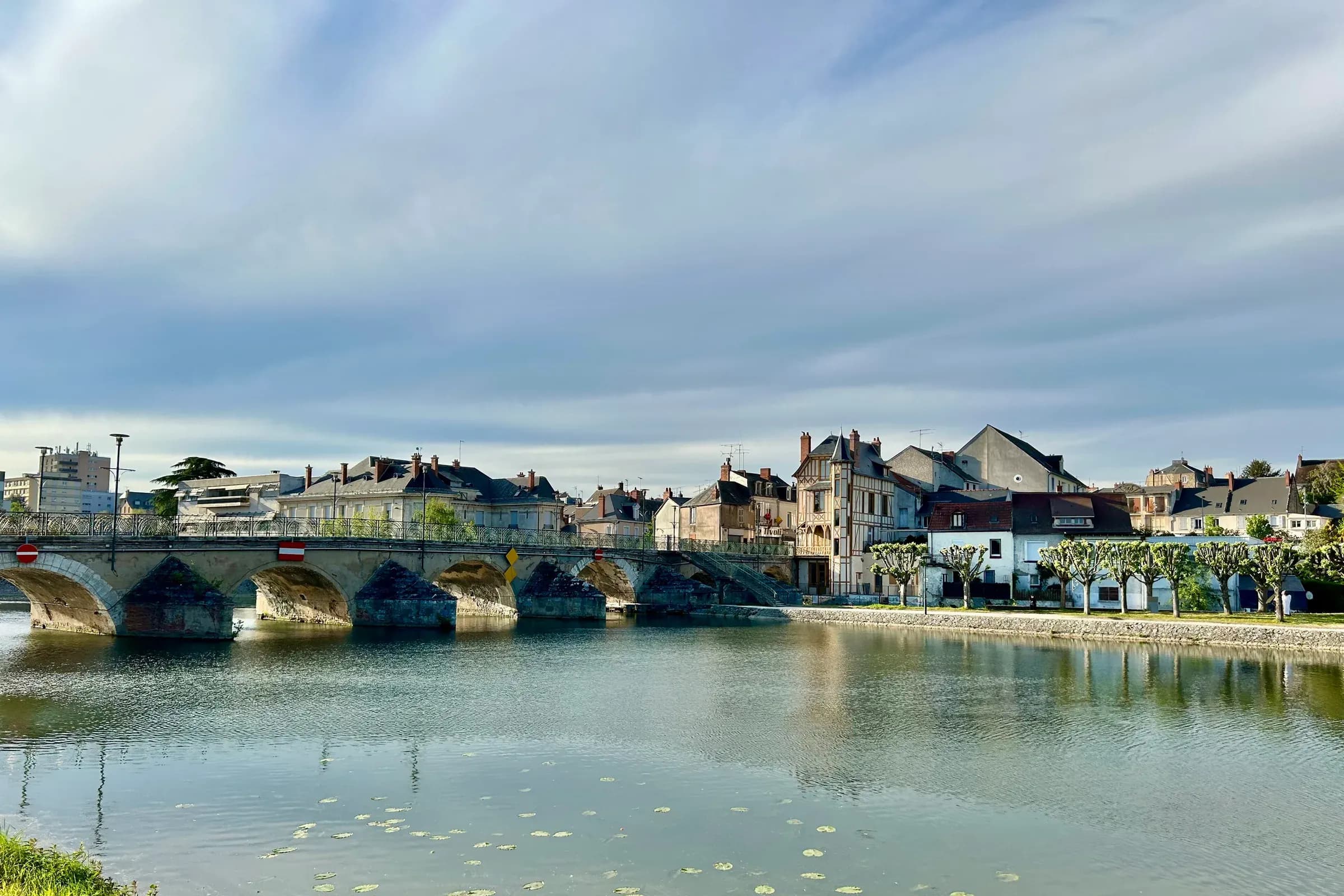 Bridge and town centre façades of Vierzon mirrored in the water, from the Quai du Bassin